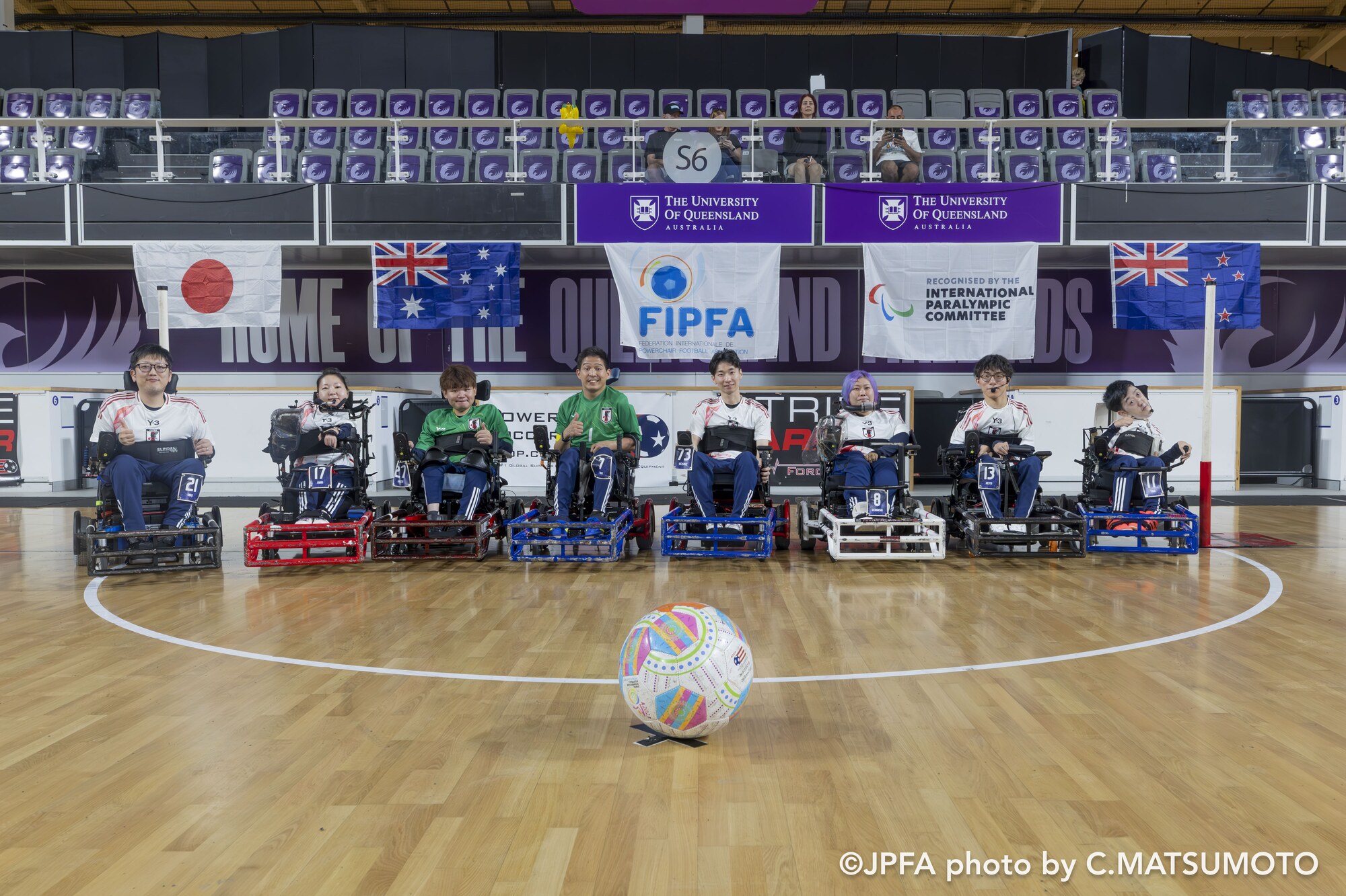 ブリスベンのセンターサークルに並ぶ電動車椅子サッカー日本代表の8選手とボール